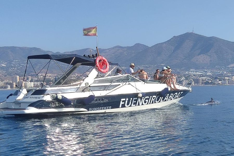 Yacht Sun and a dolphin with the Fuengirola mountains behind